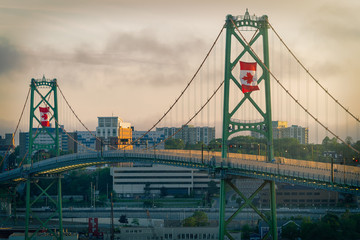 The Angus L MacDonald Bridge at dusk on Canada Day with large Canadian flags flying. - obrazy, fototapety, plakaty