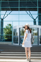 Young traveler tourist woman with backpack take pictures on retro vintage photo camera on crosswalk at international airport. Female passenger traveling abroad on weekends getaway. Air flight concept.