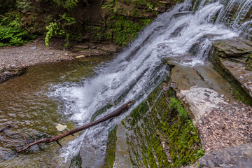 Fototapeta premium Waterfall with fallen tree in it and Rock Cliff