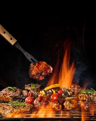 Afwasbaar Fotobehang Grill / Barbecue Biefstuk op de grill met vlammen