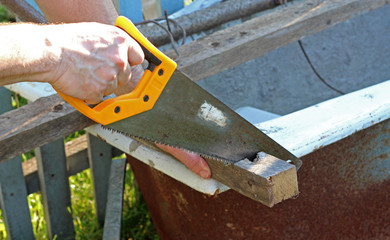 man sawing a bar with a hacksaw