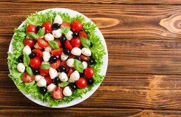 Salad with basil , tomatoes , olives and mozzarella