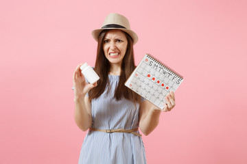 Portrait of sad woman in blue dress holding white bottle with pills, female periods calendar, checking menstruation days isolated on background. Medical healthcare, gynecological concept. Copy space.