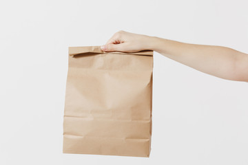 Close up female holds in hand brown clear empty blank craft paper bag for takeaway isolated on...