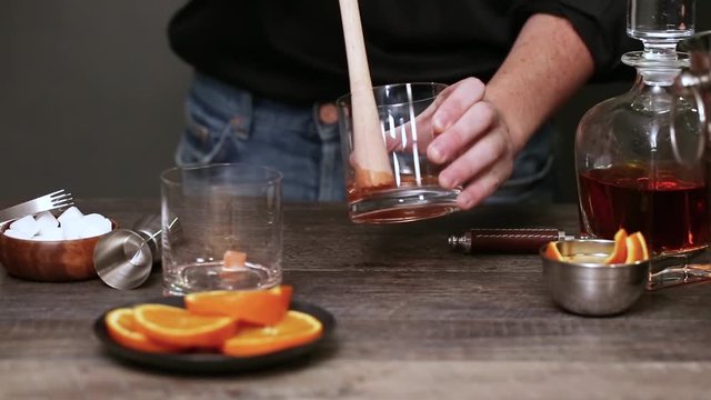 Step by step. Muddling sugar cubes in a glass for Bourbon old fashioned cocktail at home bar