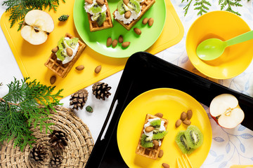 Healthy food. Picnic in nature. Breakfast with waffles, kiwi, almond, soft cheese, apple, milk on white background. Top view, flat lay.