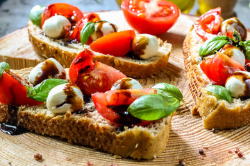 Caprese bruschetta toasts with cherry tomatoes, mozzarella and basil. Selective focus