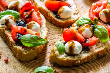 Caprese bruschetta toasts with cherry tomatoes, mozzarella and basil. Selective focus