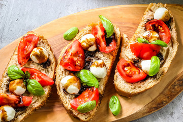 Caprese bruschetta toasts with cherry tomatoes, mozzarella and basil. Top view
