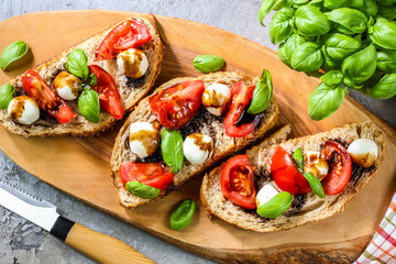 Caprese bruschetta toasts with cherry tomatoes, mozzarella and basil. Top view