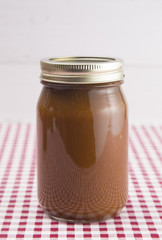 Apple Butter on a Red Gingham Table Cloth in a Home Canning Jar