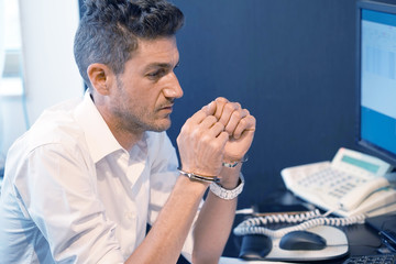 Close-up. Arrested hacker man handcuffed hands. Businessman in office in handcuffs holding a bribe....