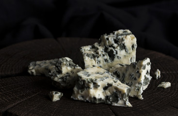 Danish blue cheese on black wooden background, with copy space