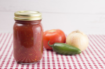 Salsa on a Red Gingham Table Cloth in a Home Canning Jar