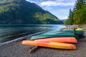 Row of colorful kayaks lying on the shore of Lake Crescent on late afternoon, Olympic National...