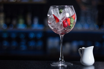 A glass of wine and white milk pitcher stand on the bar counter