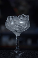 Tableware for a bar. A glass chalet full of ice is on the bar counter with bar background