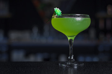 A glass with an alcoholic  cocktail Cezaritz with gin, cucumber and elderberry decorated with a flower stands on a bar counter.  Сocktail card, cocktail menu 