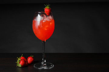 Red cocktail with strawberries on a black background.