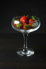 A glass chalet full of juicy strawberries  is on the wooden table