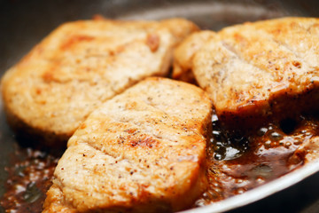 Pieces of pork in cooking with a lot of grease in a frying pan. 