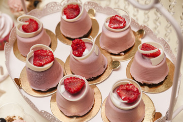 Pink frosting cookies/lava cake topped with pink frosting, white chocolate and raspberries on a lace decorative platter.