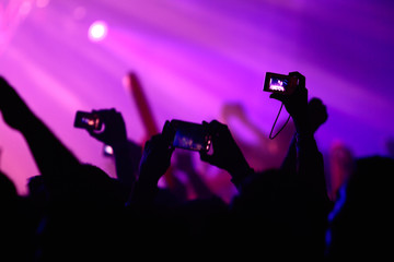 People take pictures with point and shoot cameras and cell phones at a rave party concert