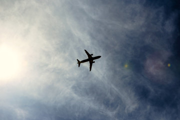 A silhouette of a plane flying overhead on a clear day.