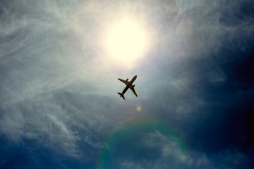 A silhouette of a plane flying overhead on a clear day.