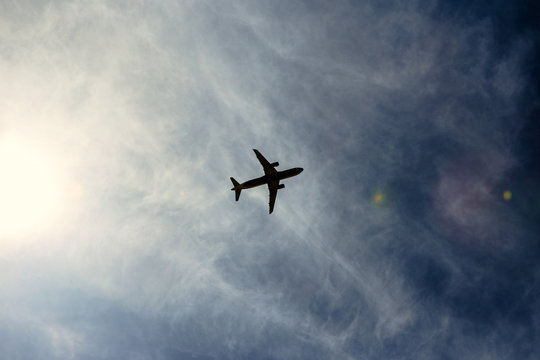 A silhouette of a plane flying overhead on a clear day.