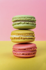 Colorful french macaroons on pink and yellow background