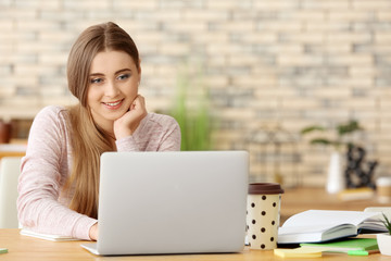 Teenage girl with laptop studying indoors