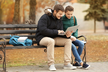 Obraz premium Teenagers with laptop studying in park