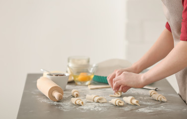 Obraz na płótnie Canvas Woman preparing tasty croissants on table in kitchen, closeup