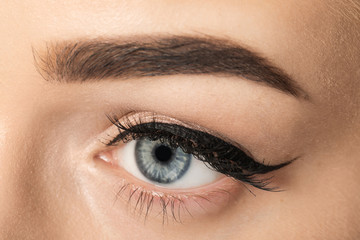 Eye of young woman with beautiful eyebrow after correction, closeup
