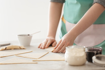 Obraz na płótnie Canvas Woman preparing tasty croissants with chocolate paste on table, closeup