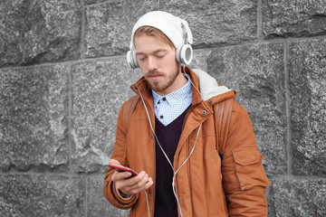 Portrait of handsome hipster with headphones listening to music outdoors