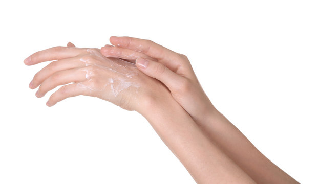 Young woman applying cream onto her hands on white background, closeup