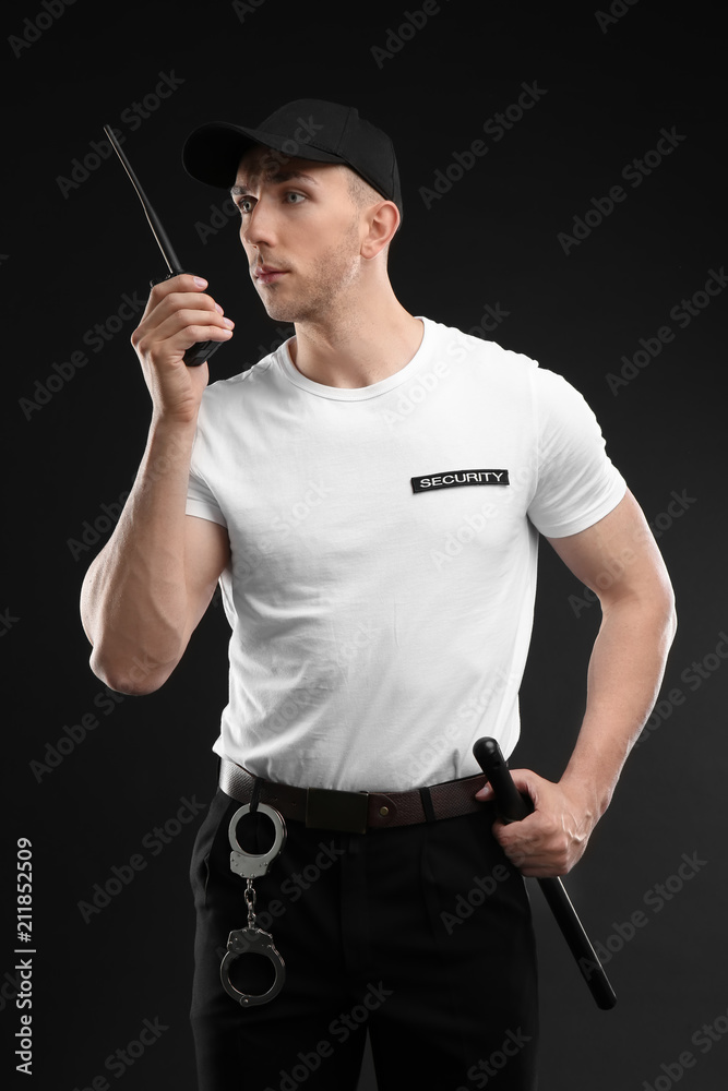 Wall mural Male security guard using portable radio transmitter on dark background