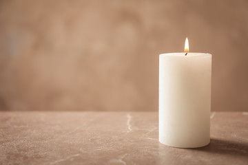 Fototapeta na wymiar Beautiful burning wax candle on table against grey background
