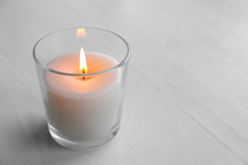 Obraz na płótnie Canvas Beautiful burning wax candle in glass on table