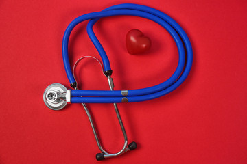 Flat lay composition with stethoscope and heart model on color background