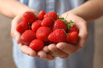 Young woman holding fresh ripe strawberries, closeup