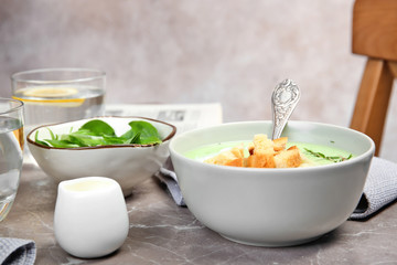 Green pea soup with croutons in bowl on table