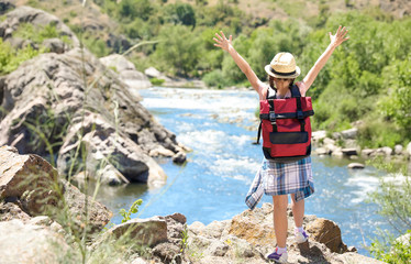 Little girl on rock near river. Summer camp