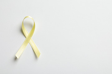 Yellow ribbon on white background, top view. Cancer awareness
