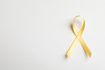 Yellow ribbon on white background, top view. Cancer awareness