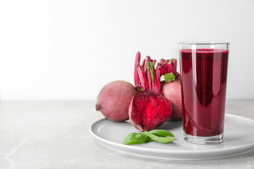 Glass of fresh beet juice, basil and vegetable on table