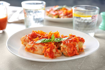 Plate with stuffed cabbage leaves in tomato sauce on table