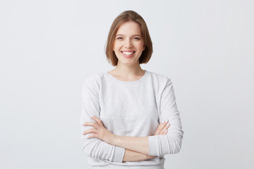 Portrait of cheerful attractive young woman in longsleeve standing with arms crossed and smiling...